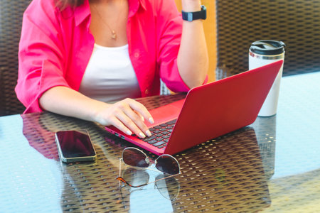 A girl in works on a laptop in a cafe at a remote job with a phone on the tableの写真素材