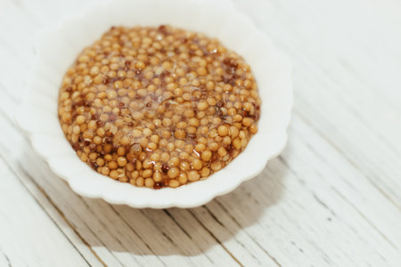 grain mustard in a white bowl on a white table.の写真素材
