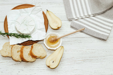 Camembert cheese with pear and rosemary sprig with honey on the table.の写真素材