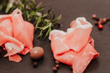 Pieces of dried pork jamon prosciutto with olives on a black board.の写真素材