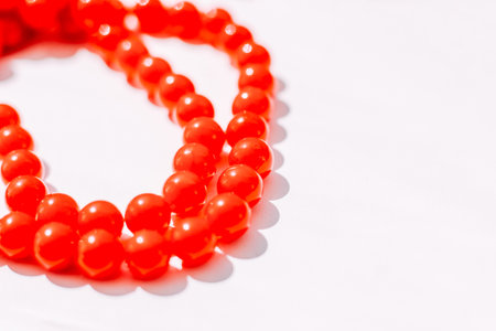 A necklace of red beads on a white aesthetic background.の写真素材