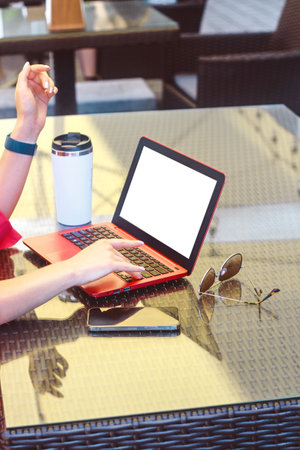 A girl in works on a laptop in a cafe at a remote job with a phone on the tableの写真素材