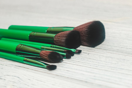 Green makeup brushes on a wooden table.の写真素材