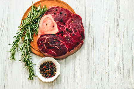 Fresh piece of meat large beef steak on the bone ossobuco with pepper, rosemary on the board.の写真素材