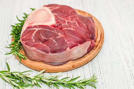 Fresh piece of meat large beef steak on the bone ossobuco with rosemary sprig.の写真素材