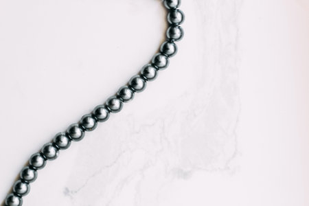 A necklace of gray beads on a white aesthetic background.の写真素材