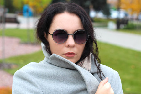 stylish curly girl in coat and glasses portraitの写真素材