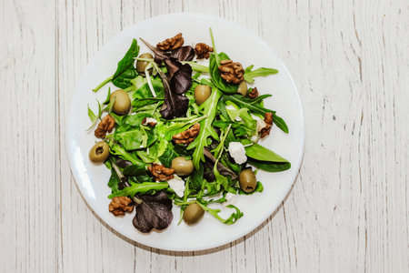 Salad leaves with arugula, cheese, green olives and nuts in a plate, healthy diet salad.の写真素材