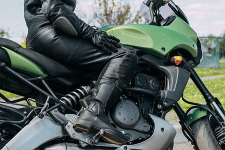 A girl sits on a motorcycle in protective moto overalls, safety equipment