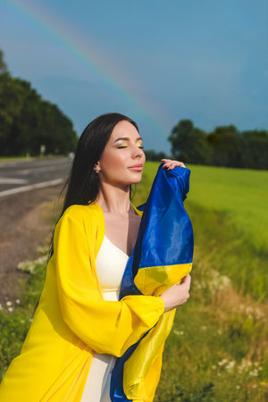 Ukrainian girl with a blue-yellow flag in her hands on the background of the fieldの写真素材