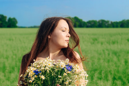 Portrait of a dark-haired girl with a bouquet of wild flowersの写真素材