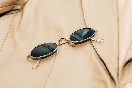Gold-rimmed sunglasses on the texture of a brown leather jacket, genuine soft leather.の写真素材