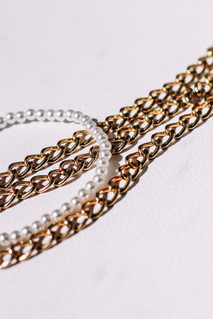 A necklace of white beads with chains of jewelry on a white aesthetic background.の写真素材