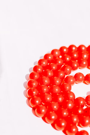 A necklace of red beads on a white aesthetic background.の写真素材