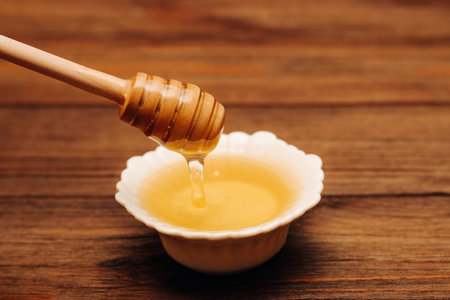 Liquid fresh linden honey in a plate with a wooden honey spoon.の写真素材