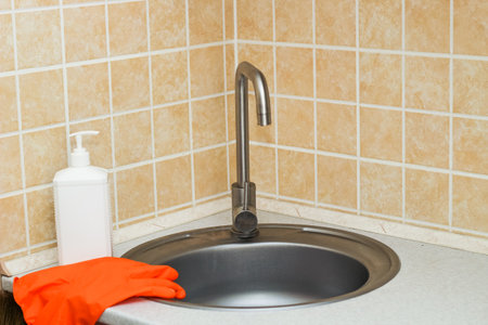 Kitchen sink with faucet and gloves for cleaning and detergent.の写真素材