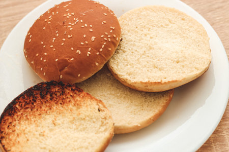 Buns for homemade burgers lie on a plate.