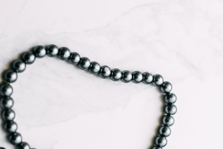 A necklace of gray beads on a white aesthetic background.の写真素材
