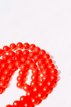 A necklace of red beads on a white aesthetic background.の写真素材