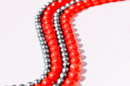 A necklace of red and gray beads on a white aesthetic background.の写真素材