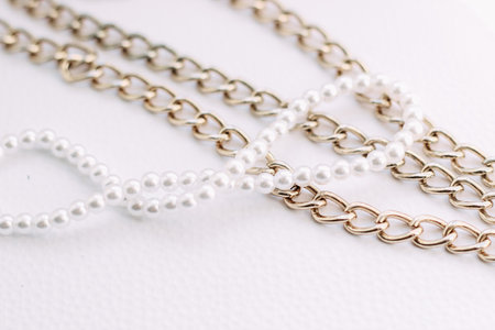 A necklace of white beads with chains of jewelry on a white aesthetic background.の写真素材