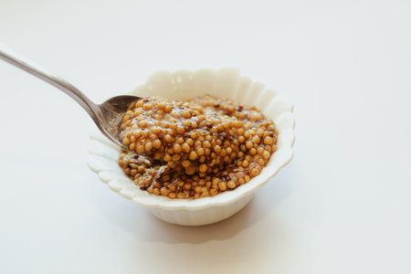 grain mustard in a white bowl on a white table.の写真素材