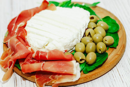 Pieces of dried pork jamon prosciutto with olives and cheese on the board.の写真素材