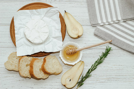 Camembert cheese with pear and rosemary sprig with honey on the table.の写真素材