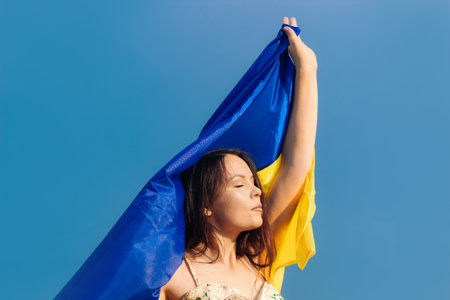Ukrainian girl with a blue-yellow flag in her hands on the background of the fieldの写真素材