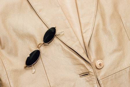 Gold-rimmed sunglasses on the texture of a brown leather jacket, genuine soft leather.の写真素材