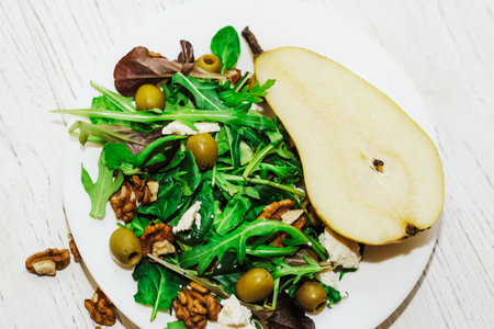 Salad with pears, herbs, arugula, prosciutto, cheese, green olives and nuts.の写真素材