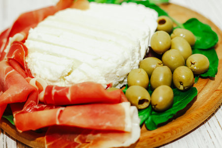 Pieces of dried pork jamon prosciutto with olives and cheese on the board.の写真素材