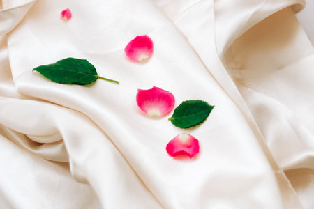 Petals of pink roses on a white silk background with space for text.の写真素材
