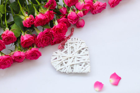 Decorative white heart made of vines, Valentine's Day on the background of a bouquet of roses.の写真素材