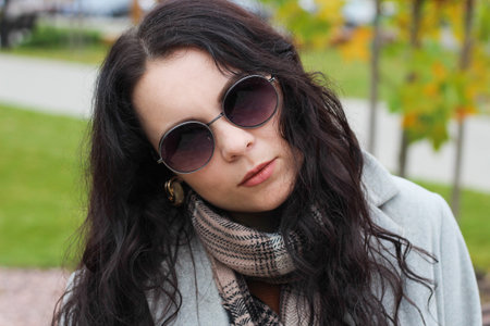 stylish curly girl in coat and glasses portraitの写真素材