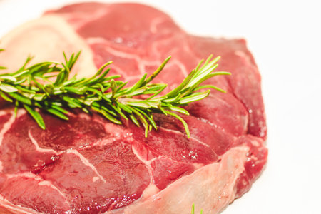 Fresh piece of meat large beef steak on the bone ossobuco with rosemary sprig.の写真素材