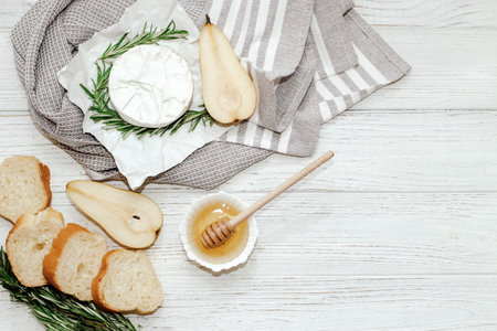 Camembert cheese with pear and rosemary sprig with honey on the table.の写真素材