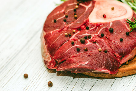 Fresh piece of meat large beef steak on the bone ossobuco with pepper, rosemary on the board.の写真素材