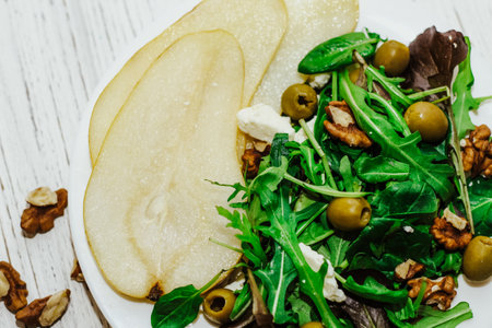 Salad with pears, herbs, arugula, prosciutto, cheese, green olives and nuts.の写真素材