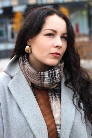 stylish curly girl in a coat with massive earrings, portraitの写真素材