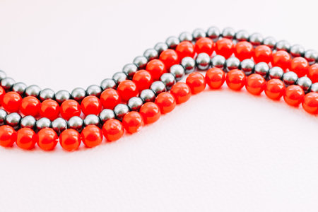 A necklace of red and gray beads on a white aesthetic background.の写真素材