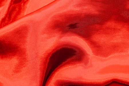 Red shiny texture of silk satin satin with folds.の写真素材