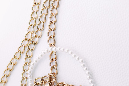 A necklace of white beads with chains of jewelry on a white aesthetic background.の写真素材