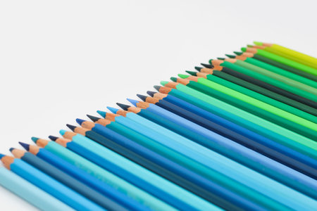 Multi-colored pencils lie on a white table, the green range of colors.の写真素材