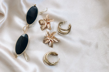 Golden jewelry on a silk beige backgroundの写真素材