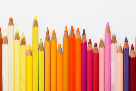 Multi-colored pencils lie on a white table, the red range of colors.の写真素材