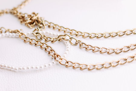A necklace of white beads with chains of jewelry on a white aesthetic background.の写真素材