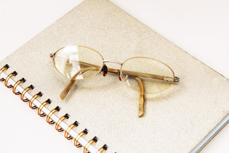 Glasses in a gold frame with diopters on a gold notebookの写真素材