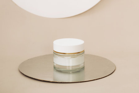 Facial care cream in a glass jar on a beige backgroundの写真素材