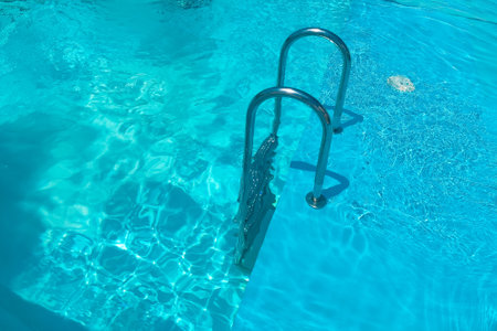Staircase in the swimming pool with blue water in the backgroundの写真素材